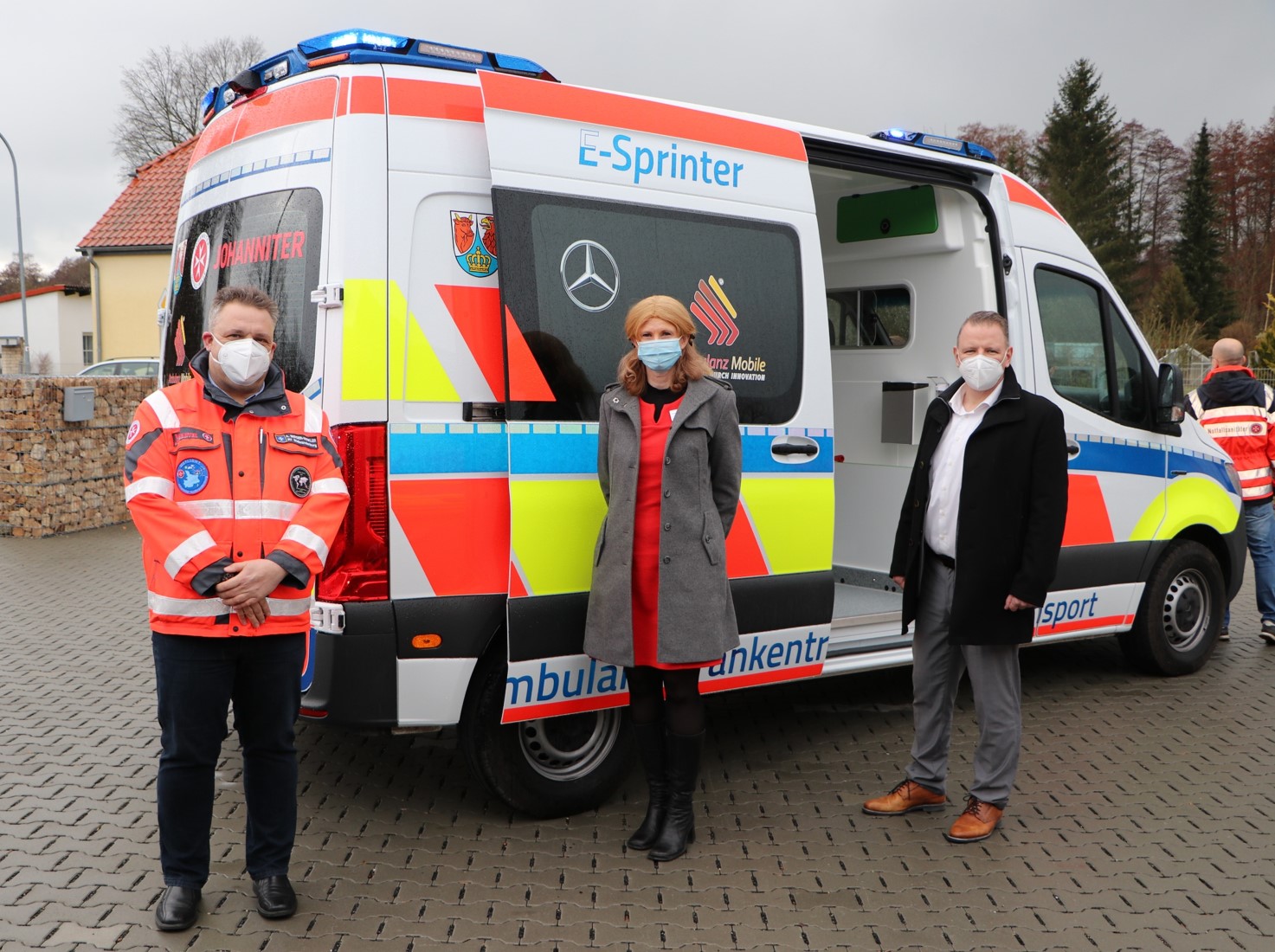 Andreas Berger-Winkler (Regionalvorstand der Johanniter-Unfall-Hilfe e. V. Regionalverband Brandenburg Süd), Susanne Rieckhof (Vizelandrätin des Landkreises Dahme-Spreewald) und Stefan Klein (Ordnungsdezernent des Landkreises Dahme-Spreewald) nehmen den ersten elektrische Krankentransportwagen in Empfang.