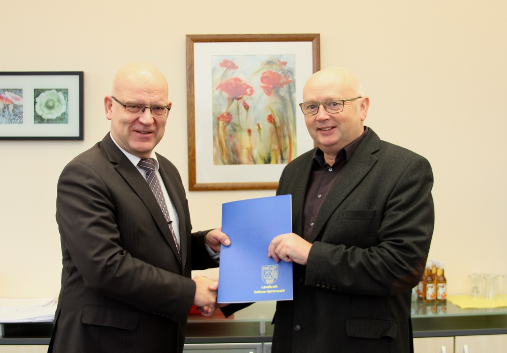 Landrat Stephan Loge (l.) übergibt Heideblicks Bürgermeister Frank Deutschmann den Zuwendungsbescheid für die Schulhofsanierung in Walddrehna (Foto: LDS)