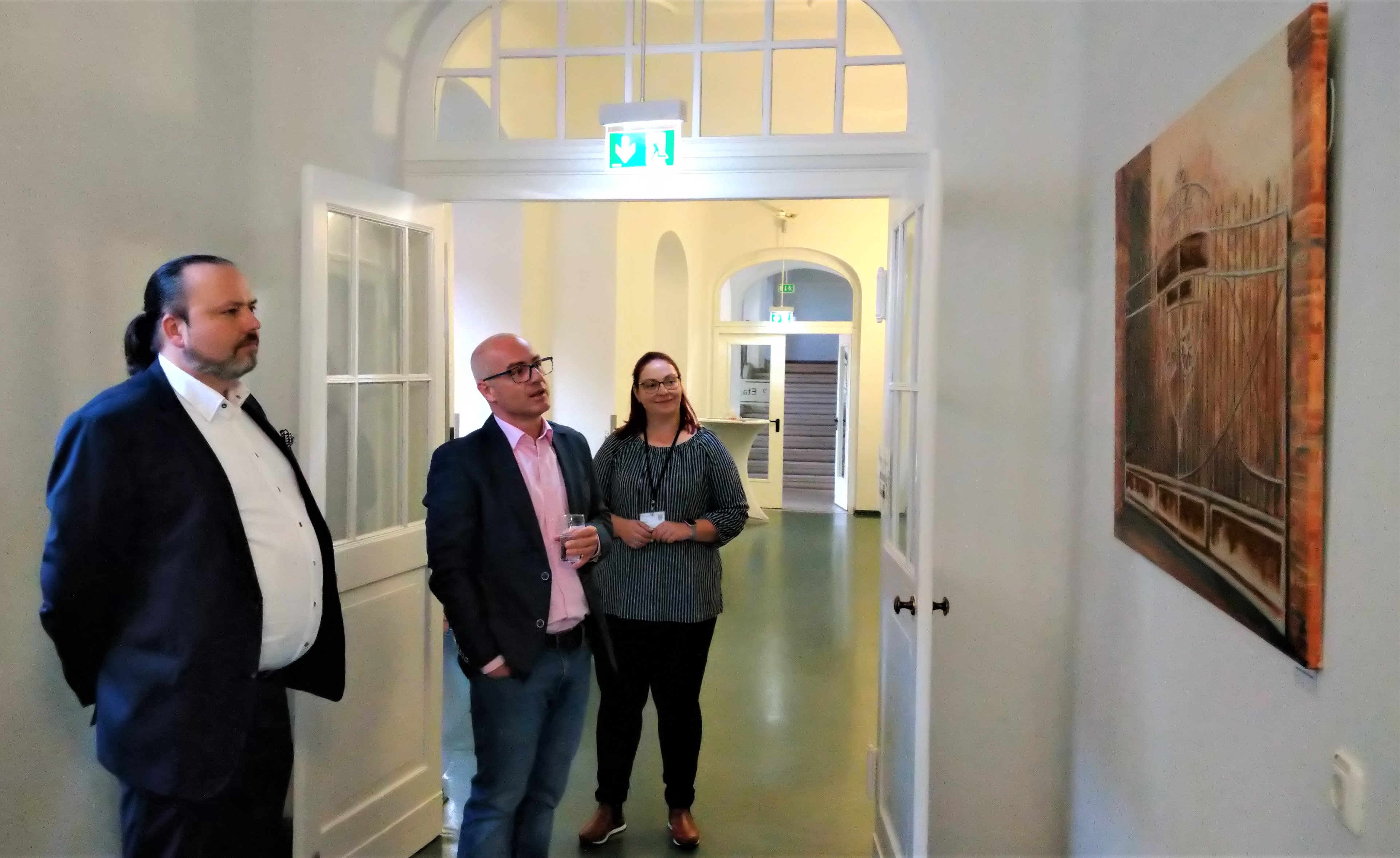Denis Kuschel erklärt Gästen der Ausstellungseröffnung, wie seine Werke entstanden sind.