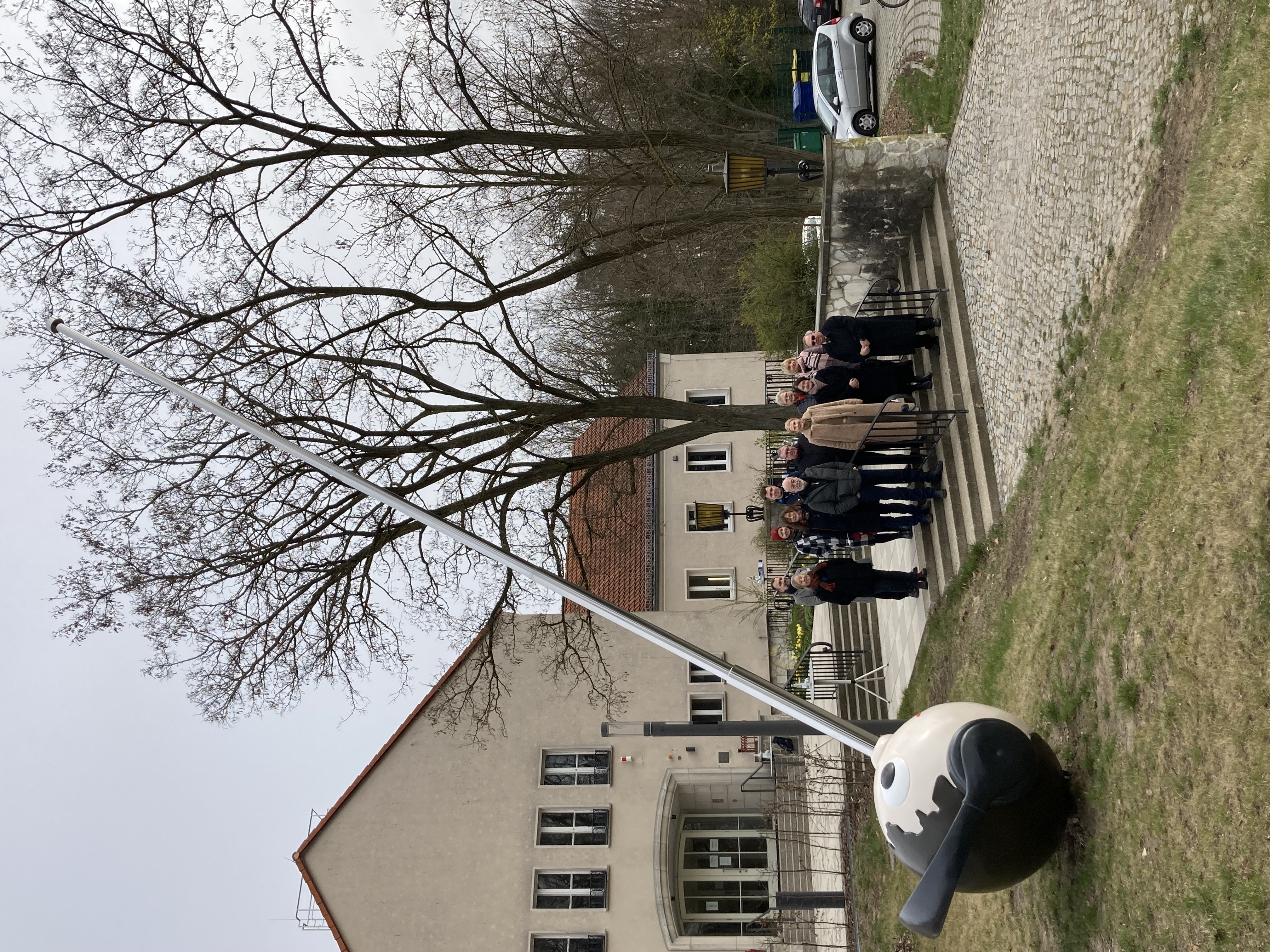Der Funker im Vordergrund, auf der Treppe die Teilnehmenden, im Hintergrund der Teil des jungen Bildungscampus - Eingang zur Schule des Zweiten Bildungsweges
