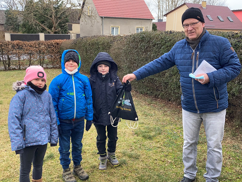 Landrat Loge übergibt den Beutel mit den Wissensheften an Leonie, Jesper und Elias aus der 1b (Foto: Landkreis Dahme-Spreewald)