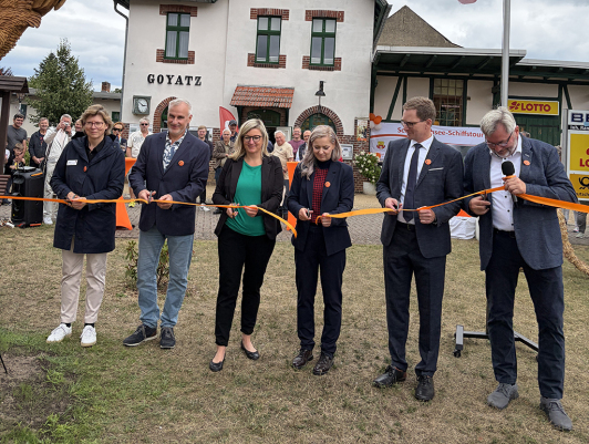 Menschengruppe schneidet orangefarbenes Band durch