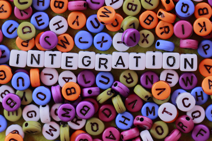 Zu sehen ist ein Bild von bunten runden buchstaben in deren mitte auf weissen Würfeln das Wort Integration liegt.