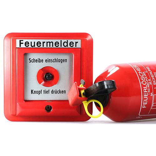 Zu sehen ist ein Feuermelder und Feuerlöscher.
