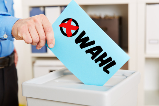 Sie sehen ein Symbolbild zur Wahl mit Stimmzettel und Wahlurne. Sie sehen ein Symbolbild zur Wahl mit Stimmzettel und Wahlurne.