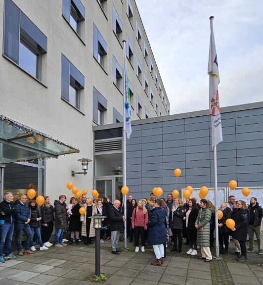 Bürgermeister der Gemeinde Schönefeld Christian Hentschel sowie viele Mitarbeitende der Gemeindeverwaltung hissen die Fahne zum internationalen Tag gegen Gewalt an Frauen am Rathaus in Schönefeld.
