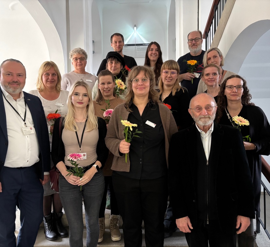 Gruppenbild zur Mitarbeiterausstellung Menschen stehen auf einer Treppe