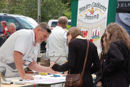 Innungsobermeister Frank Haarmann zeigt Schülerinnen, wie bunt das Maler- und Lackiererhandwerk ist.