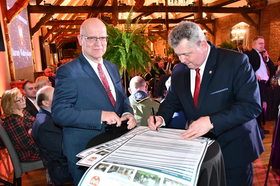 Auf dem Foto sehen Sie die Landräte Loge und Skrobisz welche den Partnerschaftskalender 2023 auf dem Neujahrempfang in Wolsztyn unterschreiben.