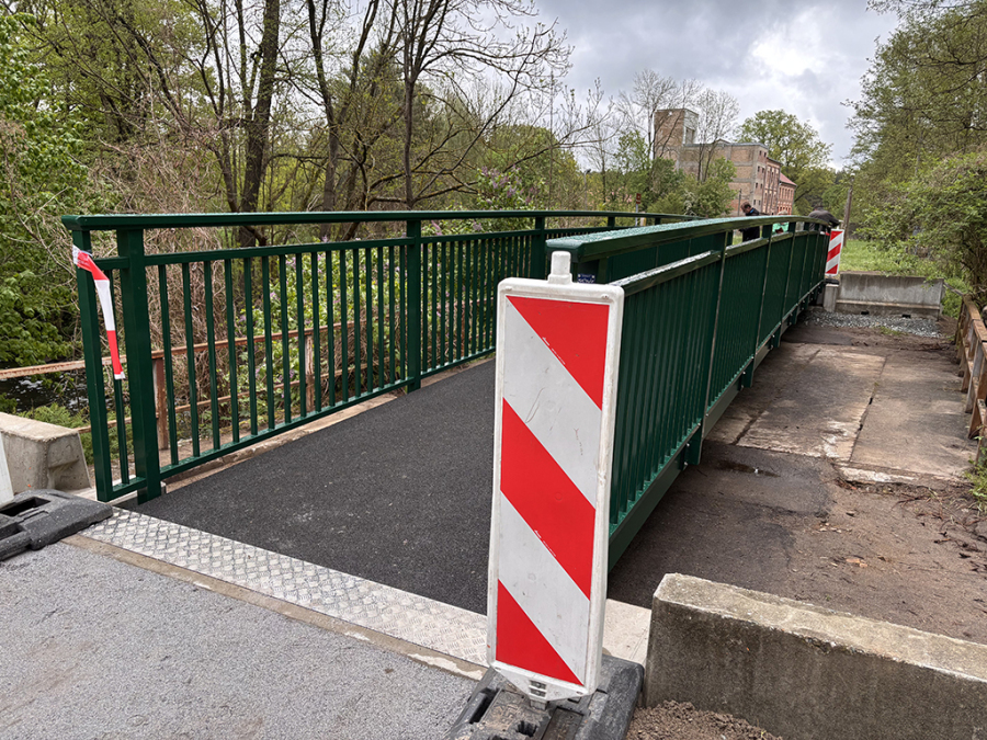 Brücke, grünes Geländer, im Hintergrund ein historisches großes Gebäude