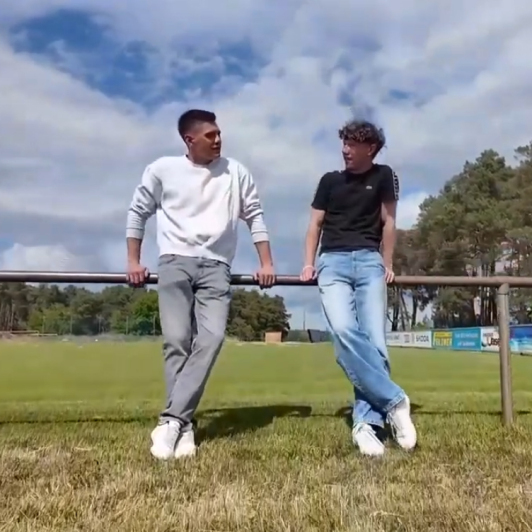 Zwei junge Männer stehen an einem sonnige Tag auf dem Fußballplatz