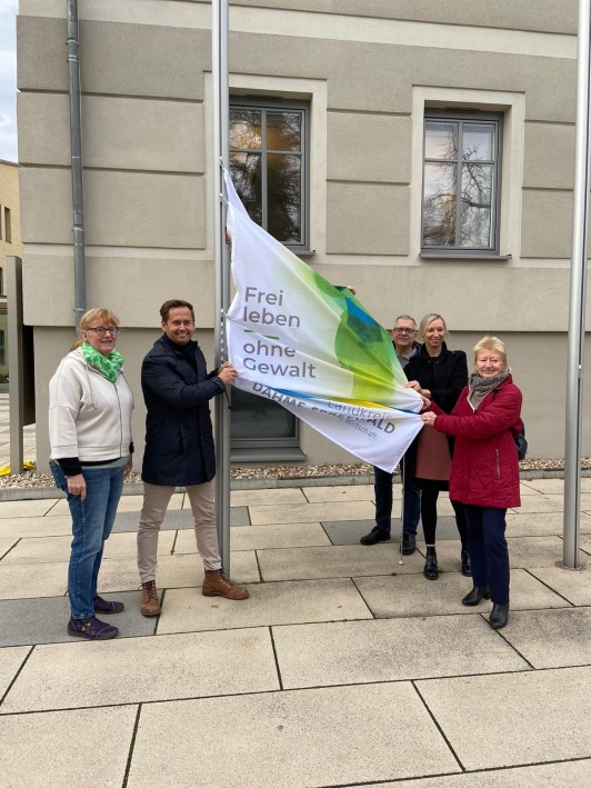 Vertreter der Stadt Königs Wusterhausen sowie LDS-Gleichstellungsbeauftragte Elke Voigt  hissen die Fahne zum internationalen Tag gegen Gewalt an Frauen am Rathaus in Königs Wusterhausen.