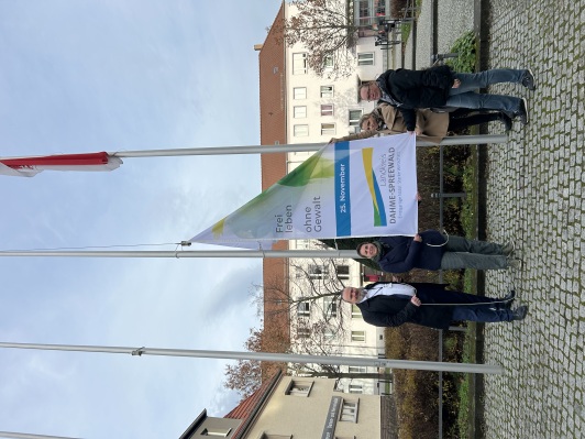 Sozialdezernent Stefan Wichary und Mitarbeitende der Gleichstellungsbeauftragten sowie Landtagsabgeordnete Nadine Graßmel hissen die Fahne zum internationalen Tag gegen Gewalt an Frauen am Standort Lübben-Reutergasse.